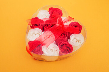 white and red soap roses in a box for Valentine's day, eau de toilette as a gift, top view, yellow background