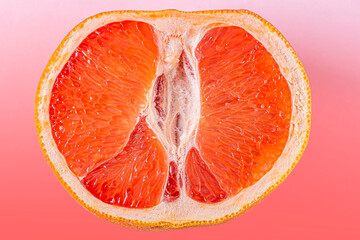 Fresh red cut grapefruit on pink background. Female health concept. Fruit as symbol of vagina. Close up.