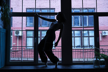 Fototapeta na wymiar dancer in the window frame in an old building. Young, elegant, graceful woman ballet dancer