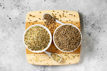 Hemp seeds. Peeled and whole dried hemp seeds in a white ceramic bowl on a light gray kitchen...