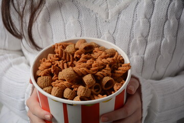 A bowl of Israeli Bissli wheat snacks with different flavors and shapes in girl's hands.