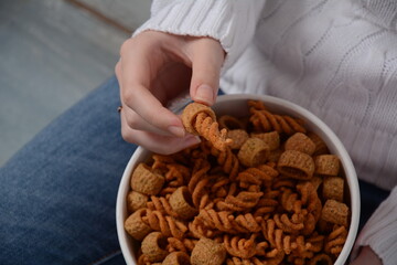 A bowl of Israeli Bissli wheat snacks with different flavors and shapes in girl's hands.