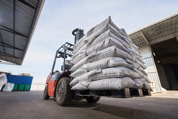 Red forklift lifts pallet with heavy bags © pridannikov