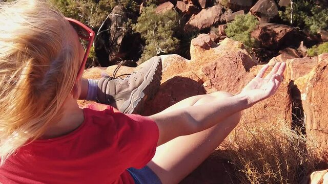 Peaceful woman doing yoga meditation in lotus pose at edge of Kings Canyon in Watarrka National Park with vertical rock walls in front. Outback Red Center, Northern Territory, Australia. SLOW MOTION