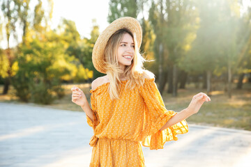 Beautiful young woman in stylish yellow dress and straw hat outdoors - Powered by Adobe