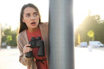 Jealous woman with binoculars spying on ex boyfriend outdoors