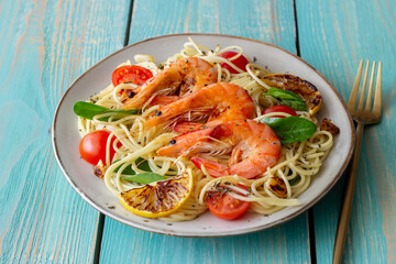 Pasta spaghetti with shrimp, tomatoes, garlic, spinach and lemon. Italian cuisine. Seafood. Diet.