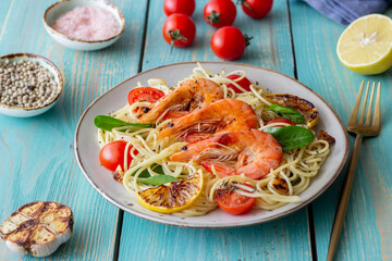 Pasta spaghetti with shrimp, tomatoes, garlic, spinach and lemon. Italian cuisine. Seafood. Diet.