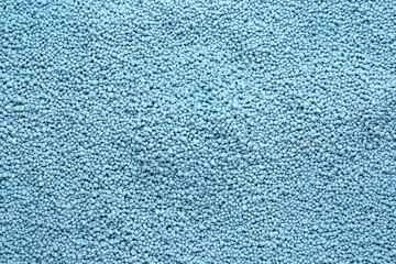 Fototapeta na wymiar Blue granular mineral fertilizer as background, top view