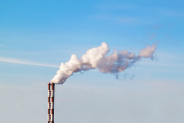 Smoking industrial stacks in thermal power plant emit polluted air into the atmosphere in blue sky