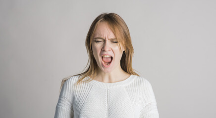 Portrait of a beautiful girl on a white background in the studio who is angry and screams