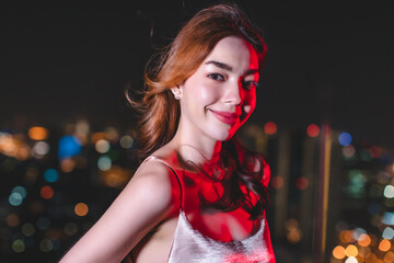 Young asian woman dancing and celebrating party new year.Young trendy ambitious woman looking intense in the camera at night next to neon light. Nightlife youth and urban atmosphere.