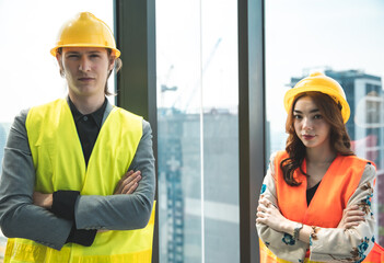 Engineers in mechanical factory reading instructions.smiling manufacture worker  man and woman stand confident with the background of white sky and building tower. Concept of industry building .