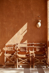 Three Hand-made chairs at a wall, with falling shadows in Oasis in UAE