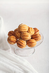 Russian traditional homemade cookies Nuts with condensed milk on a glass stand. White background, selective focus