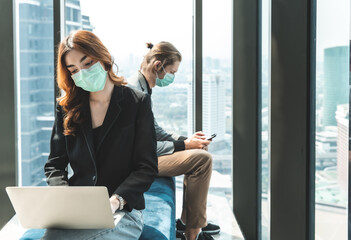 Infection of the virus coronavirus.businessman entrepreneur wears face mask standing and holding laptop with confident, with colleague in background in meeting room at modern office.