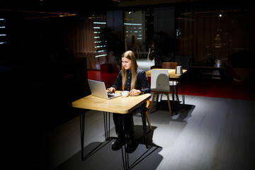 Young woman holding a cup of coffee and using laptop computer. Businesswoman working from home. Online shopping, e-commerce, work from home