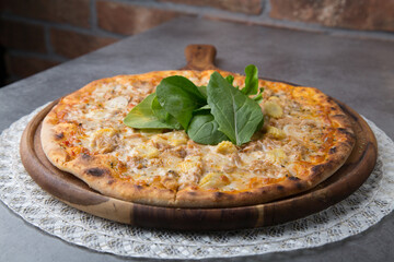 Pizza with chicken meat, onion, baby corn and rocket leaves on wooden pizza plate 