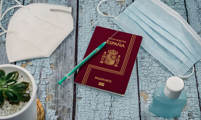 Concept of Covid vaccine tourism.  Top view of a passport and a syringe on a blue table.
