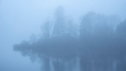 Fototapeta na wymiar Stunning landscape image of misty Derwentwater in Lake District on cold Winter morning