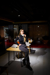 Normal working day of modern woman businessman. Beautiful young woman holding a cup of coffee while sitting at her workplace