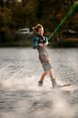 energetic guy riding on wakeboard lifting up a lot of splashes at the river