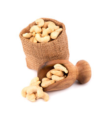 Cashew nuts in bag and wooden scoop, isolated on white background. Roasted cashew nuts.