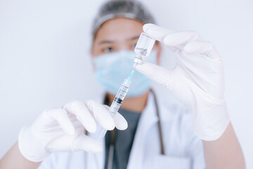 Female doctor or scientist in laboratory holding and filling a syringe with liquid vaccines, vaccination and immunization. Concept: diseases, medical care, science.