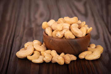 Cashew nutsin wooden bowl, on wooden background. Roasted cashew nuts.