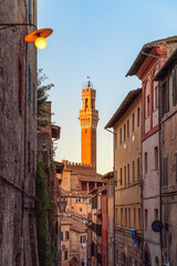 The narrow street leading to Piazza del Campo and Torre del Mangiain in Siena, Italy