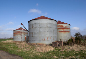 Some of the Rusting Old Style Grain silos at West Mains of Gardyne near Letham in Angus, Scotland under a bright Clear Spring morning Sky. © Julian