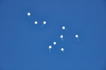 Nine white baloons floating in the blue  sky at the Sheikh Zayed Heritage Festival, UAE