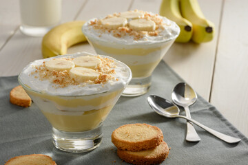 Tasty creamy dessert with banana slices and cookie crumbs