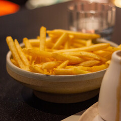 Yellow french fries in white bowl