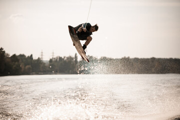 beautiful view of young sporty man jumping high on wakeboard above the water