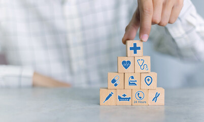 Hand arranging wood block with healthcare medical icon. Health insurance concept.