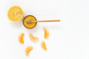 honey in a wooden bowl and orange on a white background.