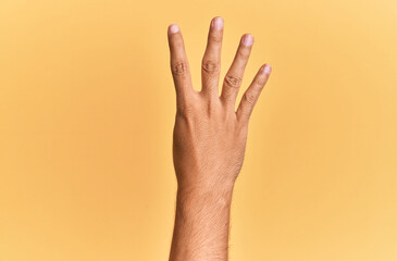 Arm and hand of caucasian man over yellow isolated background counting number 4 showing four fingers