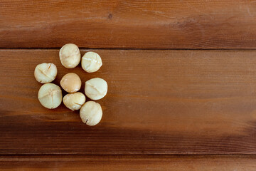 Obraz na płótnie Canvas Macadamia without peel on wooden table. Healthy product. Top view. Copy space