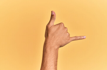 Arm and hand of caucasian man over yellow isolated background gesturing hawaiian shaka greeting gesture, telephone and communication symbol