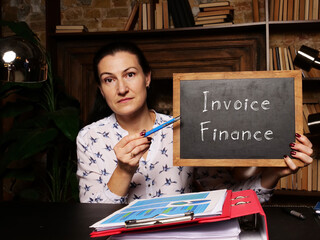 Fototapeta premium Blank chalkboard in a hand with phrase Invoice Finance . Horizontal shot.
