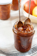 Homemade apple jam marmalade with cloves and cinnamon from organic apples in a transparent glass jar with two vintage retro spoon. Homemade autumn jam preserves.