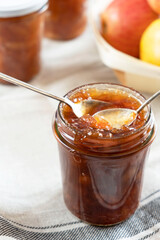 Homemade apple jam marmalade with cloves and cinnamon from organic apples in a transparent glass jar with two vintage retro spoon. Homemade autumn jam preserves.
