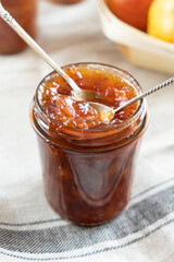 Homemade apple jam marmalade with cloves and cinnamon from organic apples in a transparent glass jar with two vintage retro spoon. Homemade autumn jam preserves.