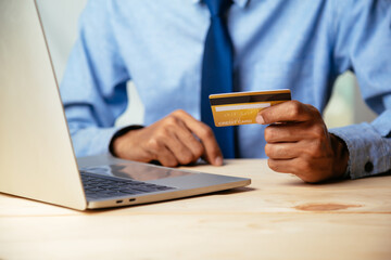 Man holding credit card and using laptop computer. Online shopping concept.