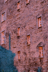 Old medieval limestone house wall with pink sunset light leaving shadows and copy space on background