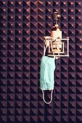 Medical mask hanging on a microphone in a closed recording studio, lockdown coronavirus