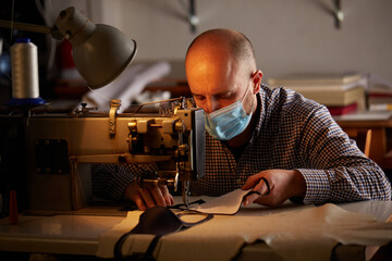 man working with sewing machine doing homemade face mask for preventing and stop corona virus spreading
