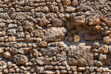 The texture of brown stone wall in a bright sunny day