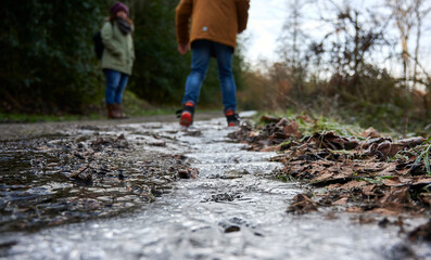 Zwei Menschen von hinten in einer Winterlandschaft mit auf dem Boden zu Eis gefrorenen Wasser im...